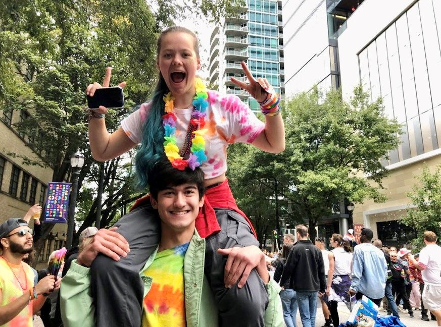 Girl on boy's shoulders smiling and watching parade
